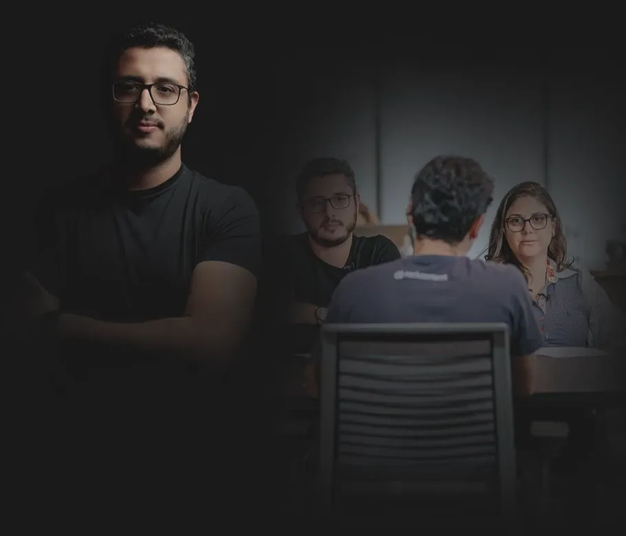 Gabriel Mineiro, de braços cruzados, à frente de um time reunido em volta de uma mesa